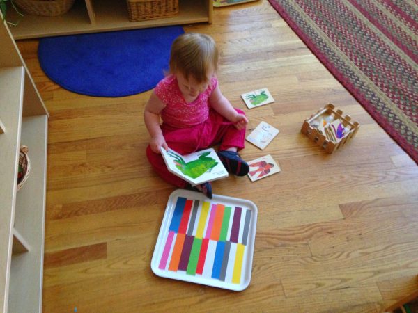 a montessori toddler student reading a book